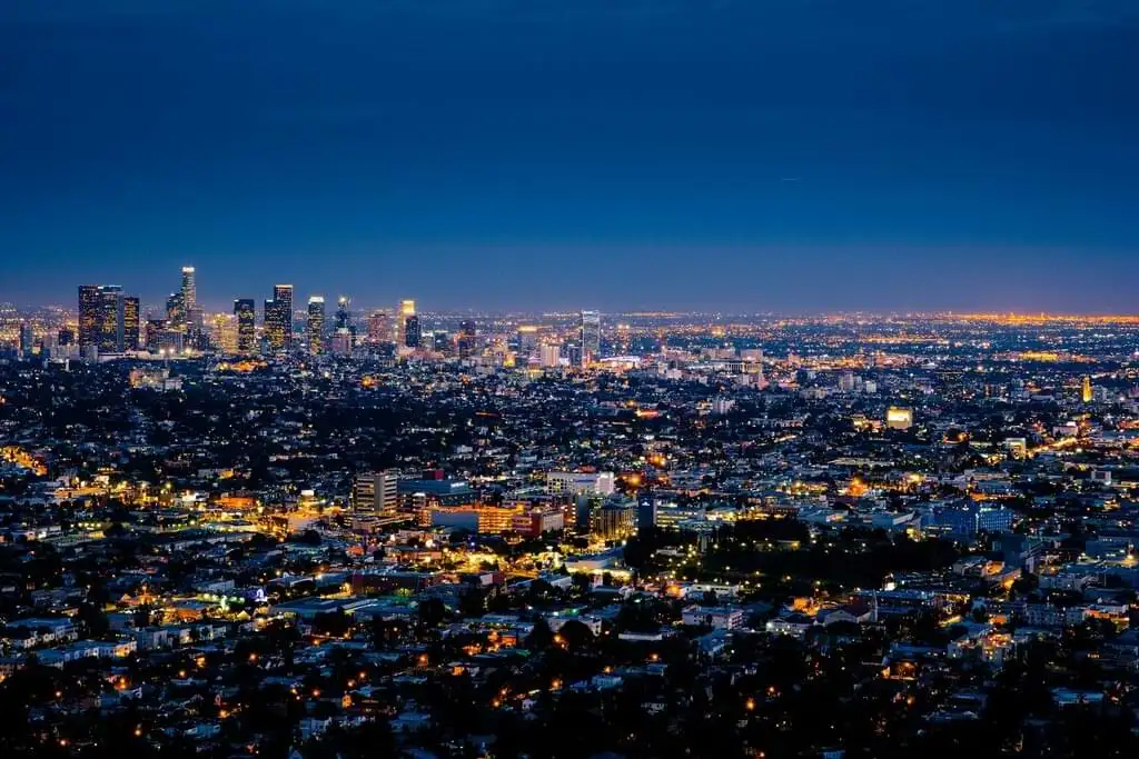 Vista panorámica nocturna de Los Ángeles con miles de luces urbanas extendiéndose bajo un cielo azul oscuro