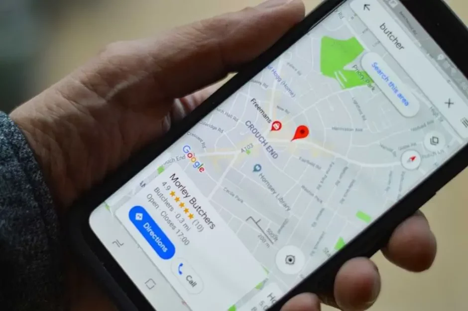 Mano sosteniendo un teléfono inteligente con la aplicación de mapas de Google abierta, mostrando la ubicación de una carnicería en un mapa urbano